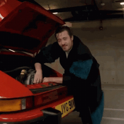 A Man Is Working On A Red Car With The Hood Up And A License Plate That Says Jyg 9Wv GIF