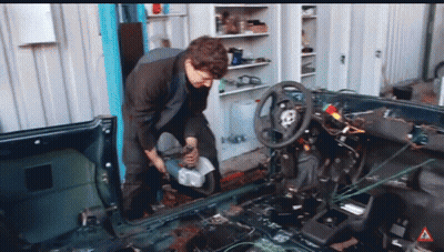A Man Is Working On The Inside Of A Car With A Warning Sign In The Corner GIF