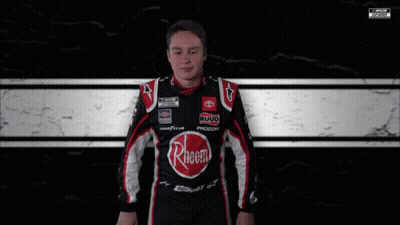 A Man Is Wrapped In A Black And White Checkered Blanket With A Nascar Logo In The Corner GIF