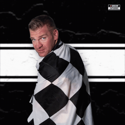 A Man Is Wrapped In A Black And White Checkered Flag With A Nascar Logo On The Bottom Right GIF