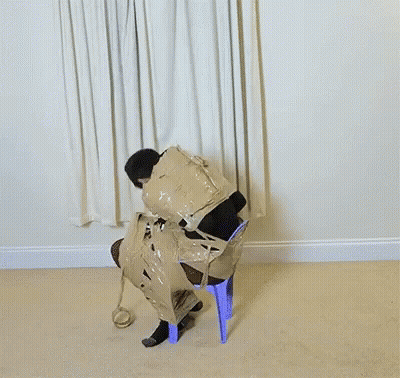 A Man Is Wrapped In Duct Tape And Sitting On A Blue Chair GIF