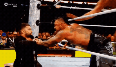 A Man Is Wrestling Another Man In A Wrestling Ring While A Crowd Watches . GIF