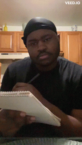 A Man Is Writing On A Piece Of Paper With The Word Veed.io On The Bottom Right GIF