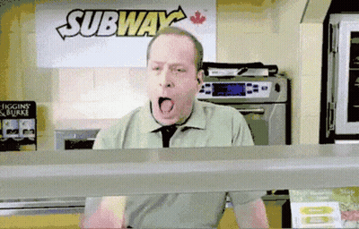 A Man Is Yawning In Front Of A Sign That Says Subway GIF