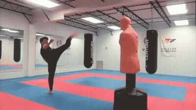 A Man Kicking A Century Boxing Bag In A Gym GIF