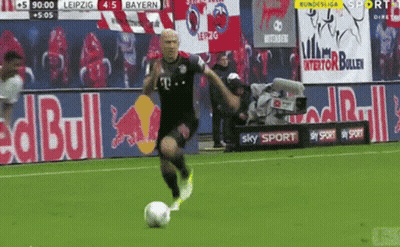 A Man Kicking A Soccer Ball On A Field With A Red Bull Ad In The Background GIF