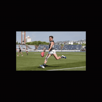 A Man Kicking A Soccer Ball On A Field With A Stadium In The Background GIF