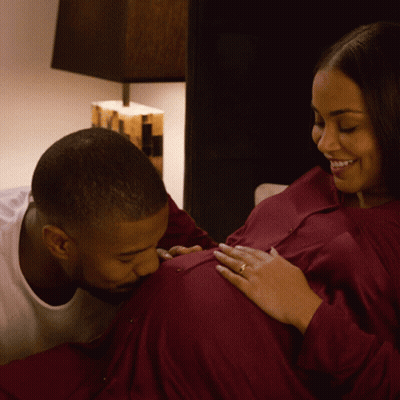 A Man Kisses A Pregnant Woman 'S Belly While She Smiles GIF