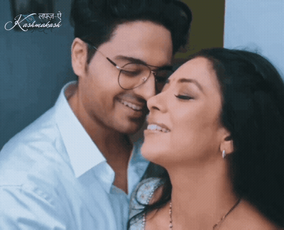 A Man Kissing A Woman On The Cheek With A Kashmakash Logo Behind Them GIF