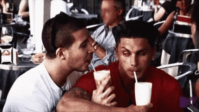 A Man Kissing Another Man On The Cheek While Drinking A Milkshake GIF
