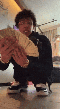 A Man Kneeling Down Holding A Stack Of Money GIF