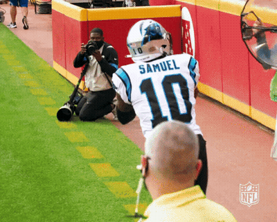 A Man Kneeling Down Taking A Picture Of A Football Player Wearing A Number 10 Jersey GIF