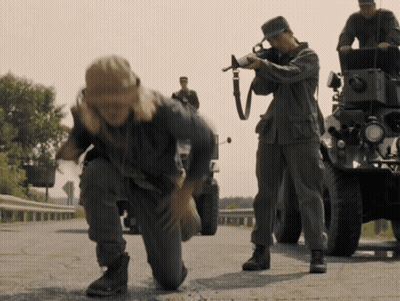 A Man Kneeling Down With A Gun While Another Man Looks On GIF