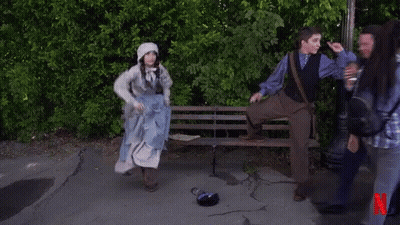A Man Kneeling On A Bench Next To A Woman In A Blue Dress With A N On The Bottom GIF