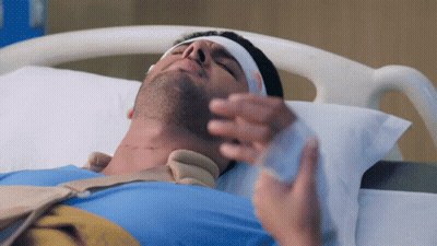 A Man Laying In A Hospital Bed With A Bandage On His Head GIF
