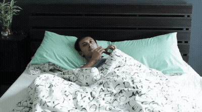 A Man Laying In Bed With A Blanket That Has The Letters Abcdefghijklmnopqrstuvwxyz Written On It GIF
