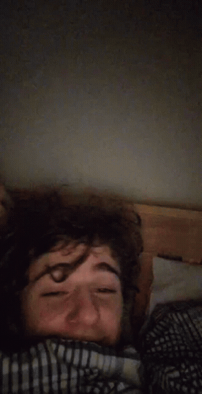 A Man Laying In Bed With His Eyes Closed And A Blanket On His Head . GIF