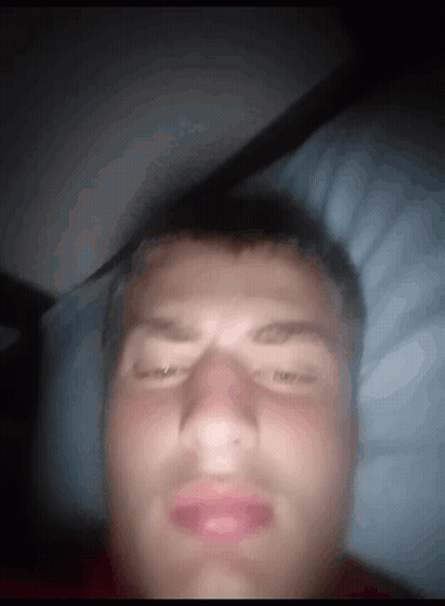 A Man Laying In Bed With His Eyes Closed And His Mouth Open GIF