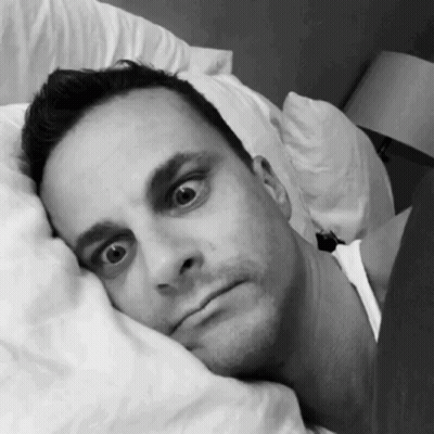 A Man Laying In Bed With His Head On A Pillow GIF
