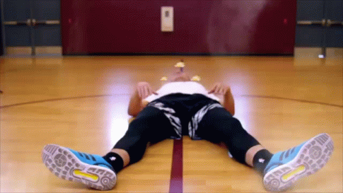 A Man Laying On A Basketball Court Wearing Blue Adidas Shoes GIF