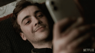 A Man Laying On A Bed Looking At His Phone With Netflix Written On The Bottom Right GIF