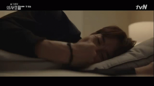 A Man Laying On A Bed With A Tvn Logo On The Bottom Right GIF
