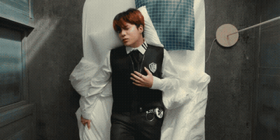 A Man Laying On A Bed With His Hand On His Chest GIF