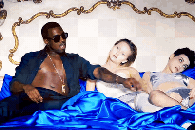 A Man Laying On A Bed With Two Women Laying On It GIF