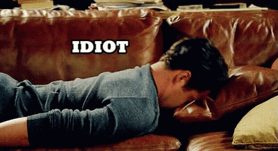 A Man Laying On A Brown Leather Couch With The Word Idiot Above Him GIF