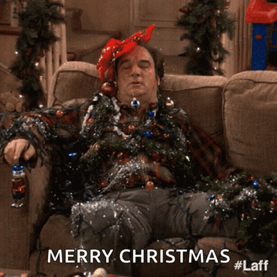 A Man Laying On A Couch Covered In Christmas Lights With The Words Merry Christmas Below Him GIF