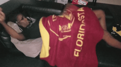 A Man Laying On A Couch With A Blanket That Says Florinsia GIF