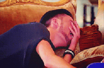 A Man Laying On A Couch With His Hand On His Face GIF