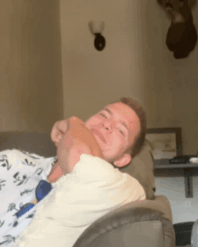 A Man Laying On A Couch With His Head On Another Person 'S Lap GIF
