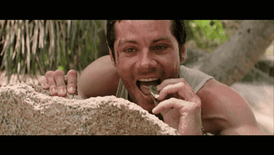 A Man Laying On A Rock Eating Something GIF