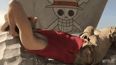 A Man Laying On A Rock In Front Of A Netflix Flag GIF