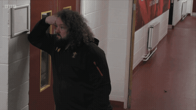 A Man Leaning Against A Wall In A Hallway With Bbc Written On The Corner GIF