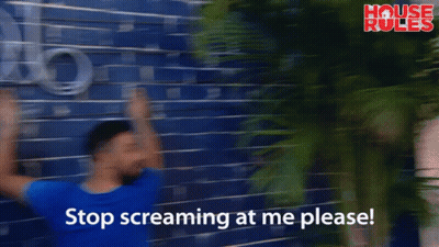 A Man Leans Against A Blue Brick Wall With The Words Stop Screaming At Me Please On The Bottom GIF