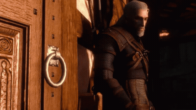 A Man Leans Against A Wooden Door With A Metal Ring On It GIF