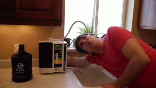 A Man Leans Over A Sink Next To A Bottle Of Energe GIF