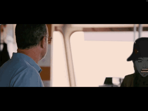 A Man Looking At A Picture Of A Man With A Hat On His Head GIF