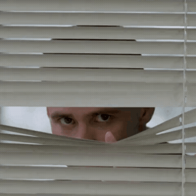 A Man Looking Through Blinds With His Hand On His Face GIF