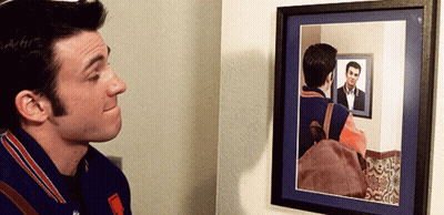 A Man Looks At His Reflection In A Mirror GIF