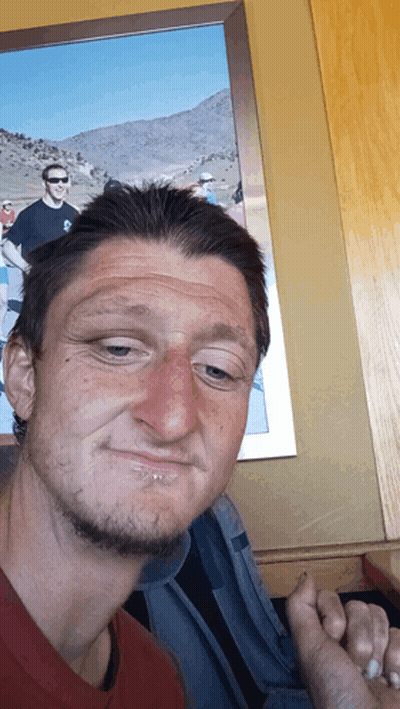 A Man Making A Funny Face In Front Of A Picture Of Two Men GIF