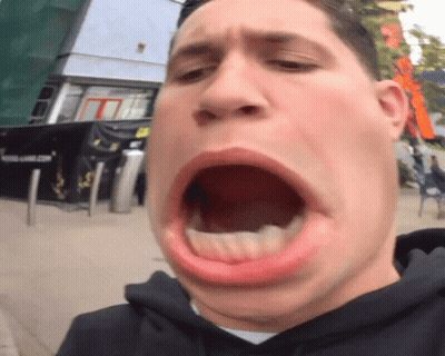 A Man Making A Funny Face With His Mouth Open In Front Of A Building That Says Young Game.com GIF