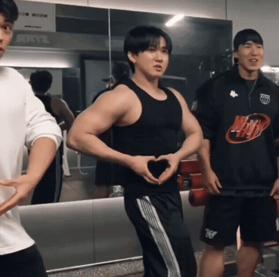 A Man Making A Heart Shape With His Hands In Front Of A Mirror In A Gym GIF