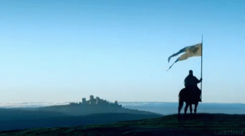 A Man On A Horse Holding A Flag In Front Of A Mountain GIF