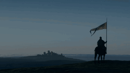 A Man On A Horse Is Holding A Flag In Front Of A Castle GIF