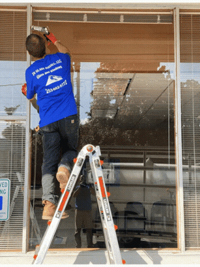 A Man On A Ladder Wearing A Blue Shirt That Says ' In Glass Install Llc ' GIF