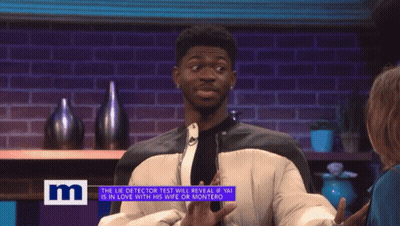 A Man On A Tv Show Talking To A Woman With The Letter M On The Bottom Right GIF