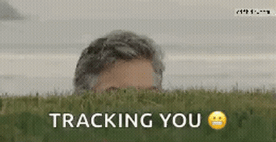 A Man Peeking Out Of The Grass With The Words " Tracking You " Written Below Him GIF
